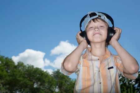 The teenager in ear-phones listens to music against the skyの写真素材