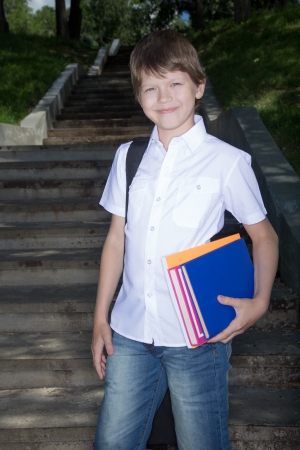 Portrait the schoolboy in white shirt with books and writing-books in handsの写真素材