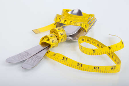 top of view of measuring tape near spoon and fork, concept of nutrition and diet on white background with space for textの写真素材