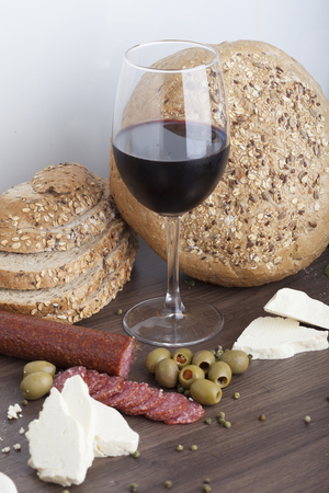 Salami sausage on a wooden table with wine and olivesの写真素材