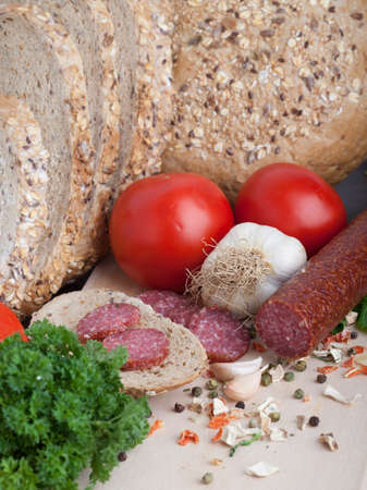 sausage slices, tomato, lettuce, bread on a wooden carving boardの写真素材
