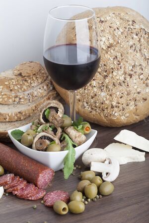 Salami sausage on a wooden table with wine, cheese and olivesの写真素材
