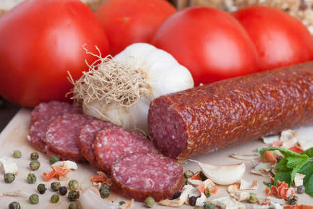 sausage slices, tomato, lettuce, bread on a wooden carving boardの写真素材