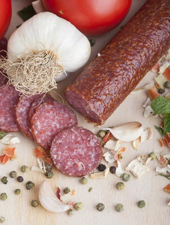 sausage slices, tomato, lettuce, bread on a wooden carving boardの写真素材