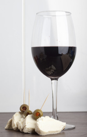 Red wine in wineglass cheese and olivesの写真素材