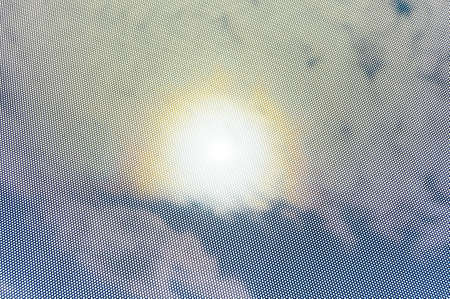 View through a dot mask towards the sky. The strong sunlight causes a halo in the sky. Depending on the zoom level of the photograph the mask may provoke different interferences. Invisible remote wire connections made visible.の写真素材
