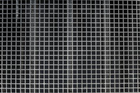 Iron grid with quadrangular pattern symbolizing a wall, border or fence containing repetitive patterns resulting from industrial production processes. Image contains traces of usage.の写真素材