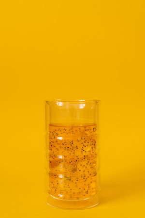 A glass of mango drink with basil seeds on a yellow background.の写真素材