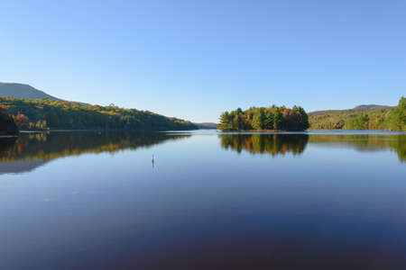 Lake with reflection of trees and mountains in the water. Beautiful autumn landscape.の写真素材