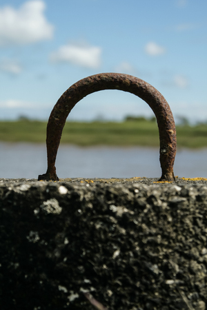 Rusty metal mooring hoop set into concrete by a lake in Scotlandの写真素材