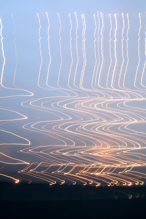 Orange zig zag light trails against a cloudy overcast sky