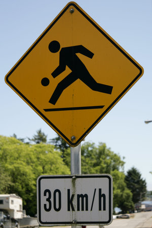 Funny yellow street sign showing children playing at 30 kmph