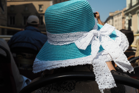 Tourist on open top bus wearing a turquoise straw hat with lacy bowの写真素材