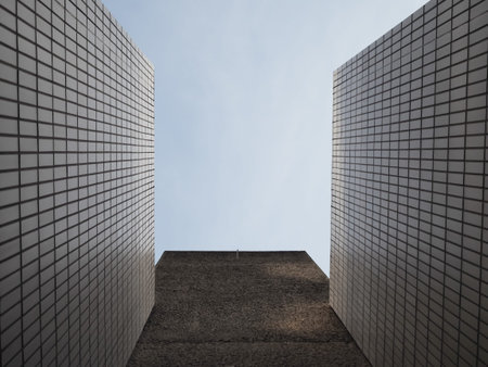 Looking up, a square of blue sky between white tiled wallsの写真素材