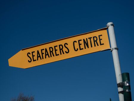 In Lyttleton, New Zealand, a yellow sign directing to Seafarers Centre where those who work at sea can rest, relax and get supportのeditorial素材