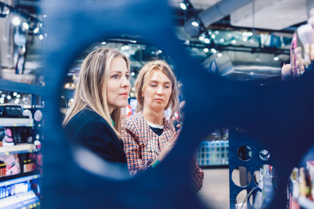 Two cheerful friends are choosing mascara and lipstick in cosmetics storeの写真素材