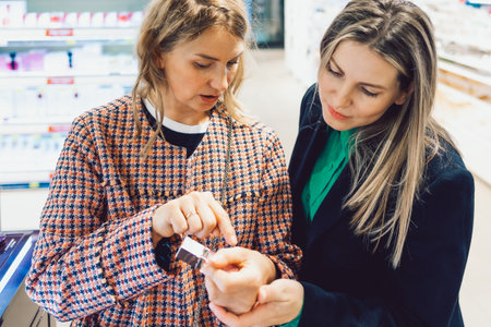 Two cheerful friends are choosing mascara and lipstick in cosmetics storeの写真素材