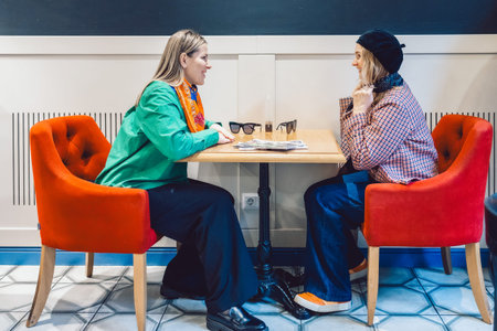 Two women met and are sitting in a cafe drinking coffee and talkingの写真素材