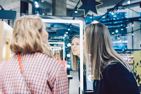 Two beautiful girls are choosing perfume in cosmetics store. High quality photo