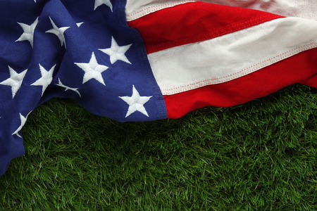 Red, white, and blue American flag on grass for Memorial Day or Veteran's day backgroundの写真素材