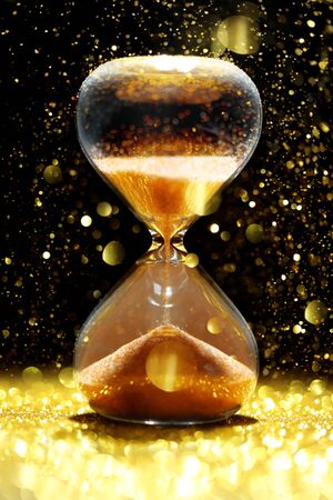 Hourglass showing the passage of time showered in golden lightの写真素材