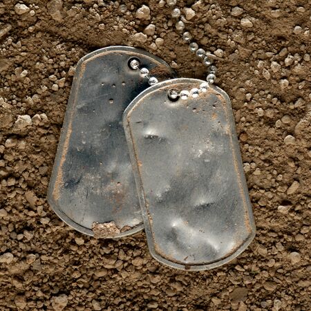 Dented and worn blank military dog tags fallen in dirtの写真素材
