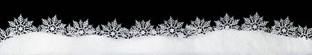 Banner of sparkling fuffy white snow with snowflakes isolated on blackの写真素材