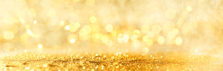 Abstract bokeh of glowing yellow lights and sparkling gold glitter background or wallpaperの写真素材