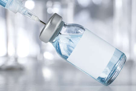 Healthcare and pharmaceutical drugs concept with syringe and vaccine vial with blue liquid. Drug vial has blank white label copyspace.の写真素材