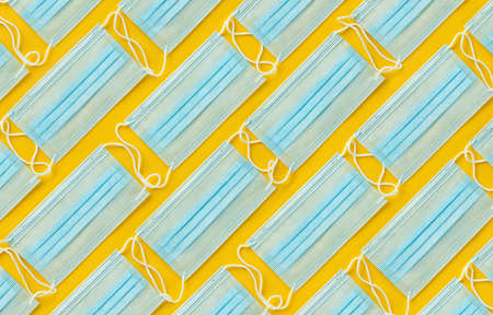 Layout of disposable medical face masks on yellow background. Personal protective equipment, PPE.の写真素材