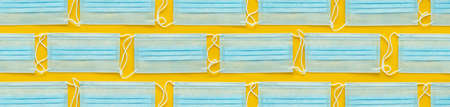 Layout of disposable medical face masks on yellow background. Personal protective equipment, PPE.の写真素材