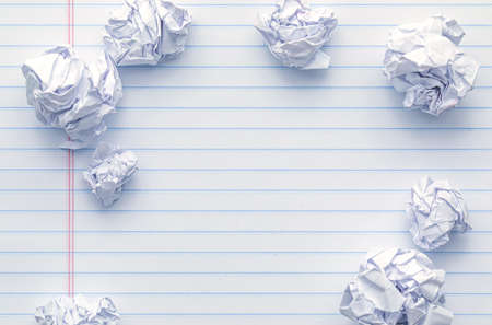 School supplies of blank lined notebook paper surrounded by more trashed balled up paper. Studying or writing mistakes concept.の写真素材