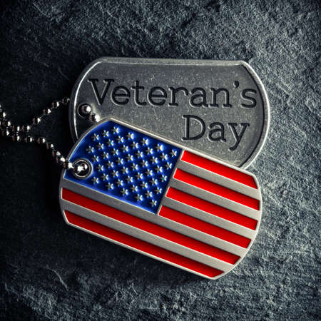 US military soldier's dog tags engraved with Veteran's Day text and in the shape of the American flag.の写真素材