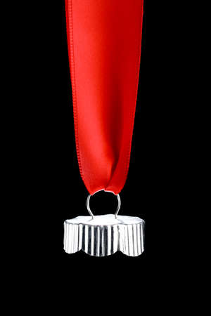 Silver top of a Christmas bauble hanging from shiny red ribbon. Empty space below ornament cap for text or product. Isolated on black.の写真素材