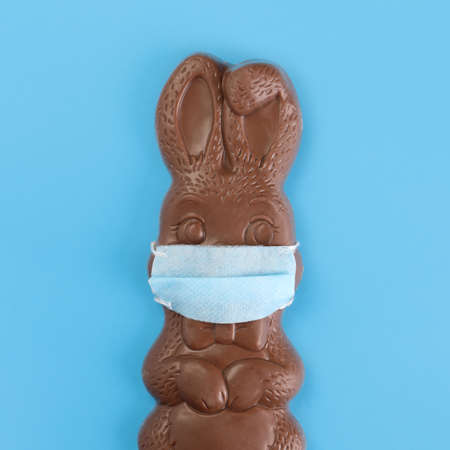 Chocolate Easter bunny wearing a medical mask. Social distancing Easter celebrations due to Covid 19 or Coronavirus safety restrictions.の写真素材