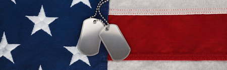 US military soldier's dog tags, rough and worn with blank space for text, on the American flag. Memorial Day or Veterans Day concept.の写真素材