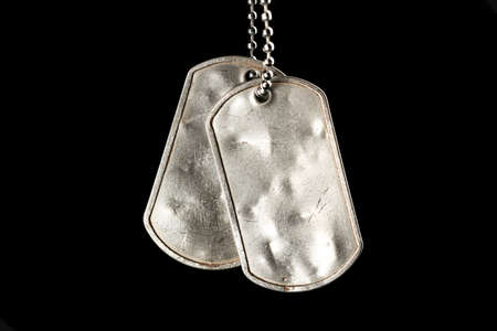 Old and worn blank military dog tags isolated on blackの写真素材