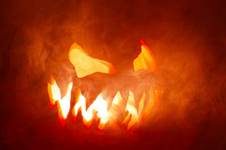 Scary Halloween jack o lantern face glowing in smoke and fire.の写真素材