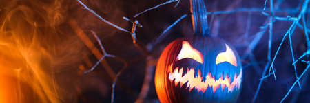 Spooky Halloween jack o lantern pumpkin with carved scary face glowing and billowing smoke in the night.の写真素材
