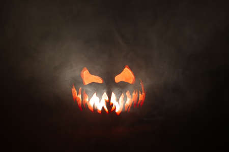 Scary Halloween jack o lantern face glowing in smoke.の写真素材