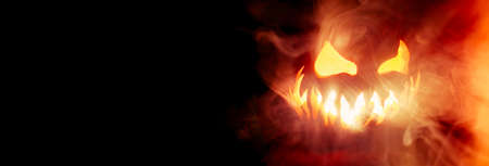 Scary Halloween jack o lantern face glowing in smoke and fire with blank copy space for text.の写真素材
