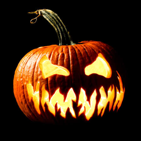 Halloween carved Jack o lantern pumpkin glowing eerily in the darkの写真素材