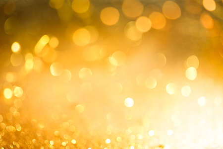 Abstract bokeh of glowing yellow lights and sparkling gold glitter background or wallpaperの写真素材