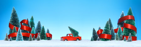 Winter wonderland with miniature tree decorations wrapped in a shiny red ribbon and a red truck with a Christmas tree on sparkling snow.の写真素材