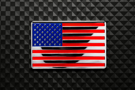 Shiny US American flag emblem on dark carbon fiber. Symbolizing USA strength, Memorial day, Veteran's day, or other patriotic event.の写真素材