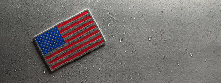 Shiny metal US American flag covered in water drops. Patriotic USA flag symbolizing the United States of America for 4th of July, Memorial day, Labor day, or other USA celebration.の写真素材
