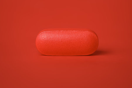 Close up of a single pill tablet in red. Concept for single dose drug, prescription, or medical cure. Blank copy space on pill.の写真素材