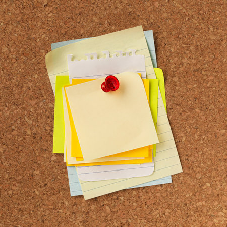Pile of blank yellow notes stacked and pinned with a red tack. Empty copy space for important office notice, message, or reminder.の写真素材