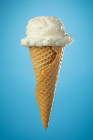 Single ice cream cone with vanilla icecream and a waffle cone on blue background.の写真素材