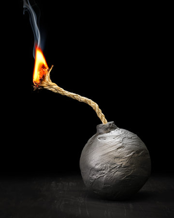 Round black bomb with lit fuse burning and smoking. Bomb about to detonate symbolizing destruction,...